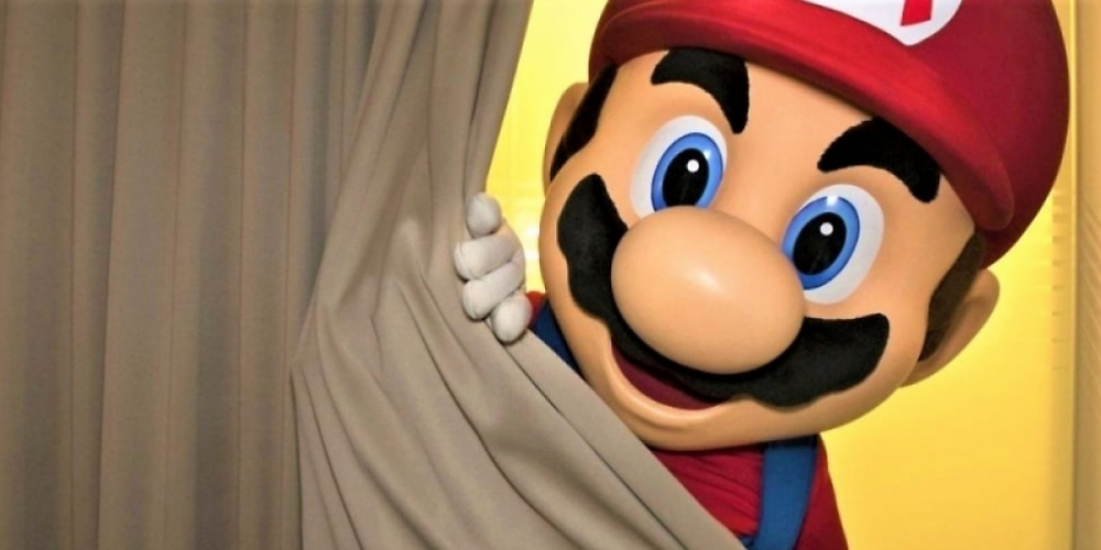 Das Nintendo-Maskottchen Super Mario spitzt hinter einem Vorhang hervor