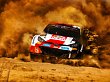 Ein Rallye-Auto rast über die Piste und wirbelt Staub auf