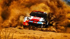 Ein Rallye-Auto rast über die Piste und wirbelt Staub auf