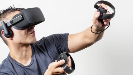 Ein Mann spielt mit zwei Bewegungscontrollern Oculus Rift.